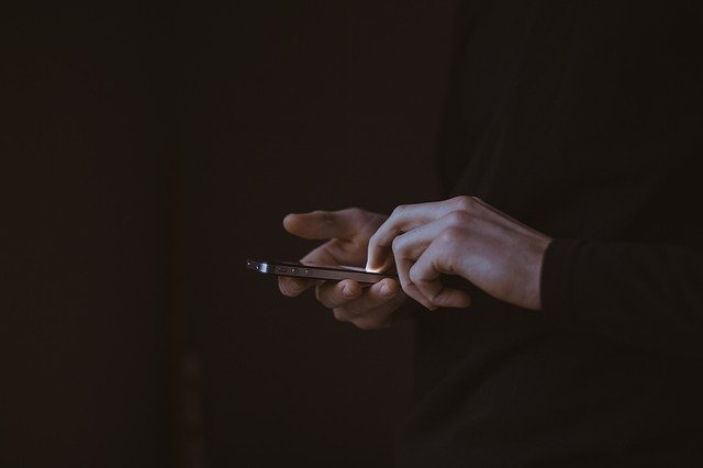 Muž v čiernom oblečení pracuje s mobilným telefónom